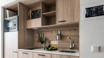 A modern kitchen with wooden cabinets, a built-in microwave, a fruit bowl, and a wall-mounted digital display.