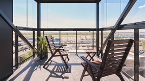 A modern interior with large windows, two wooden chairs, and a potted plant. - LURICH Residences (Tallinn)