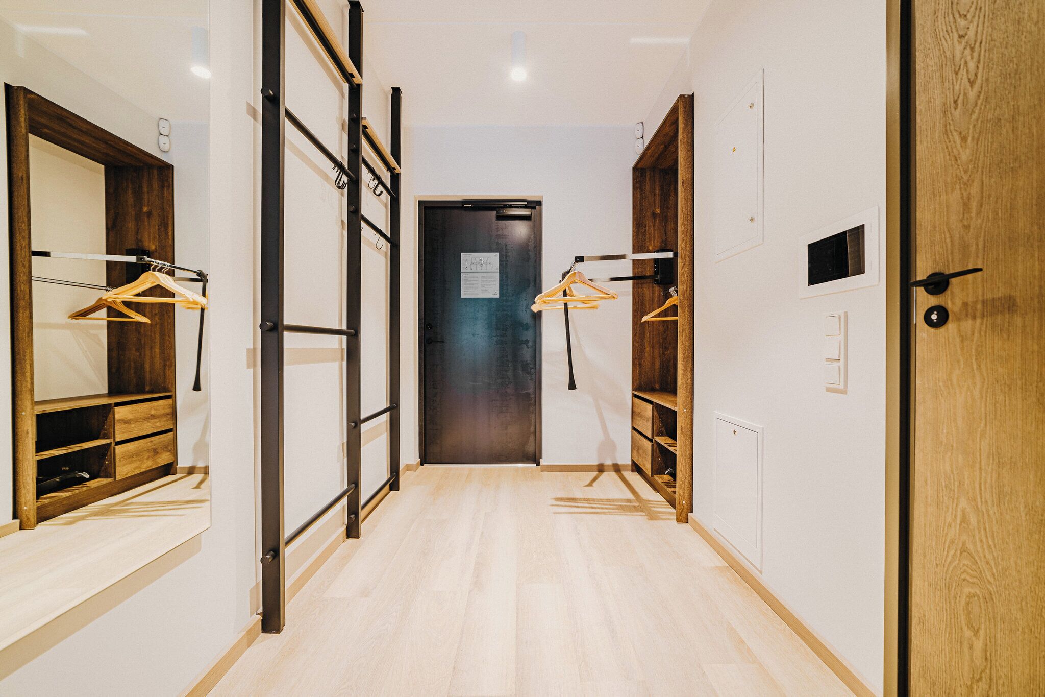 Un pasillo con suelo de madera, un espejo y puertas de madera.