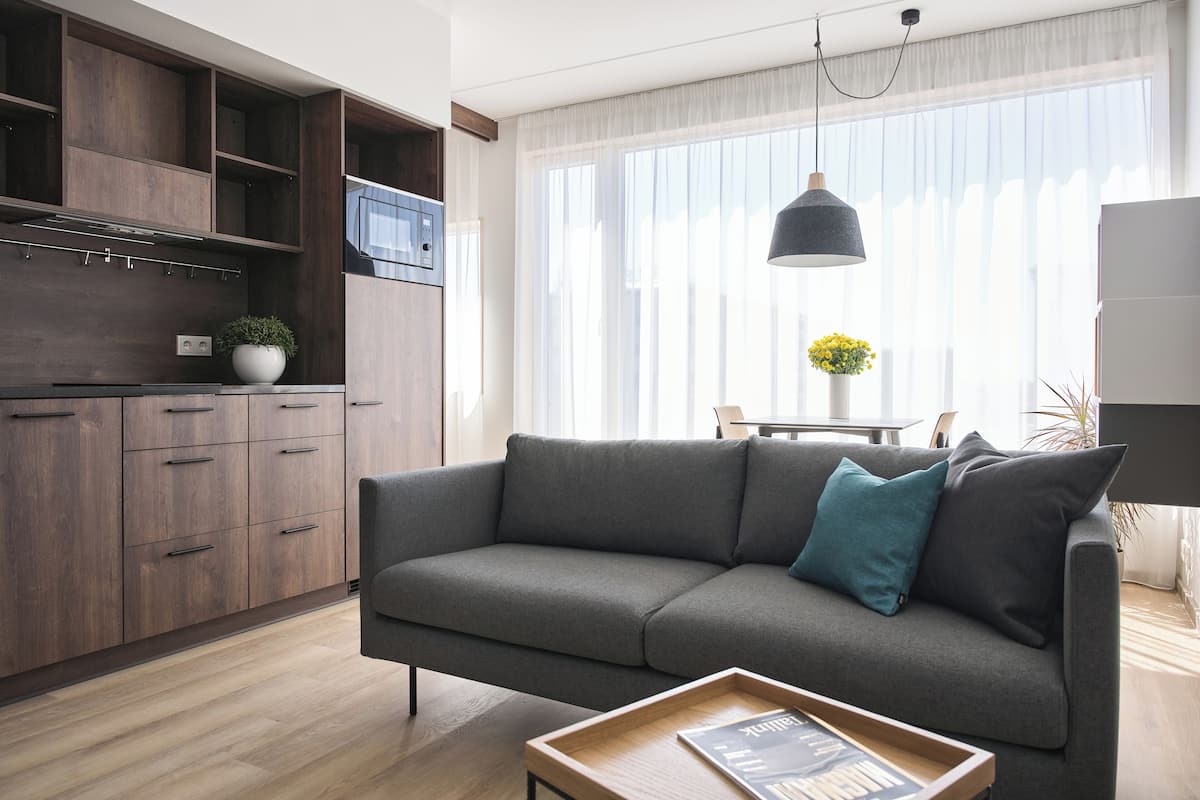 Un salon moderne avec un canapé gris, des meubles en bois et un coin repas comprenant une table et des chaises.