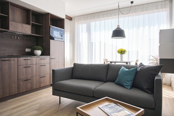 Una sala de estar moderna con un sofá gris, armarios de madera y un comedor con una mesa y sillas.