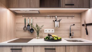 A modern kitchen with wooden cabinets, a white countertop, a sink, and a fruit bowl. - LURICH Residences (Tallinn)