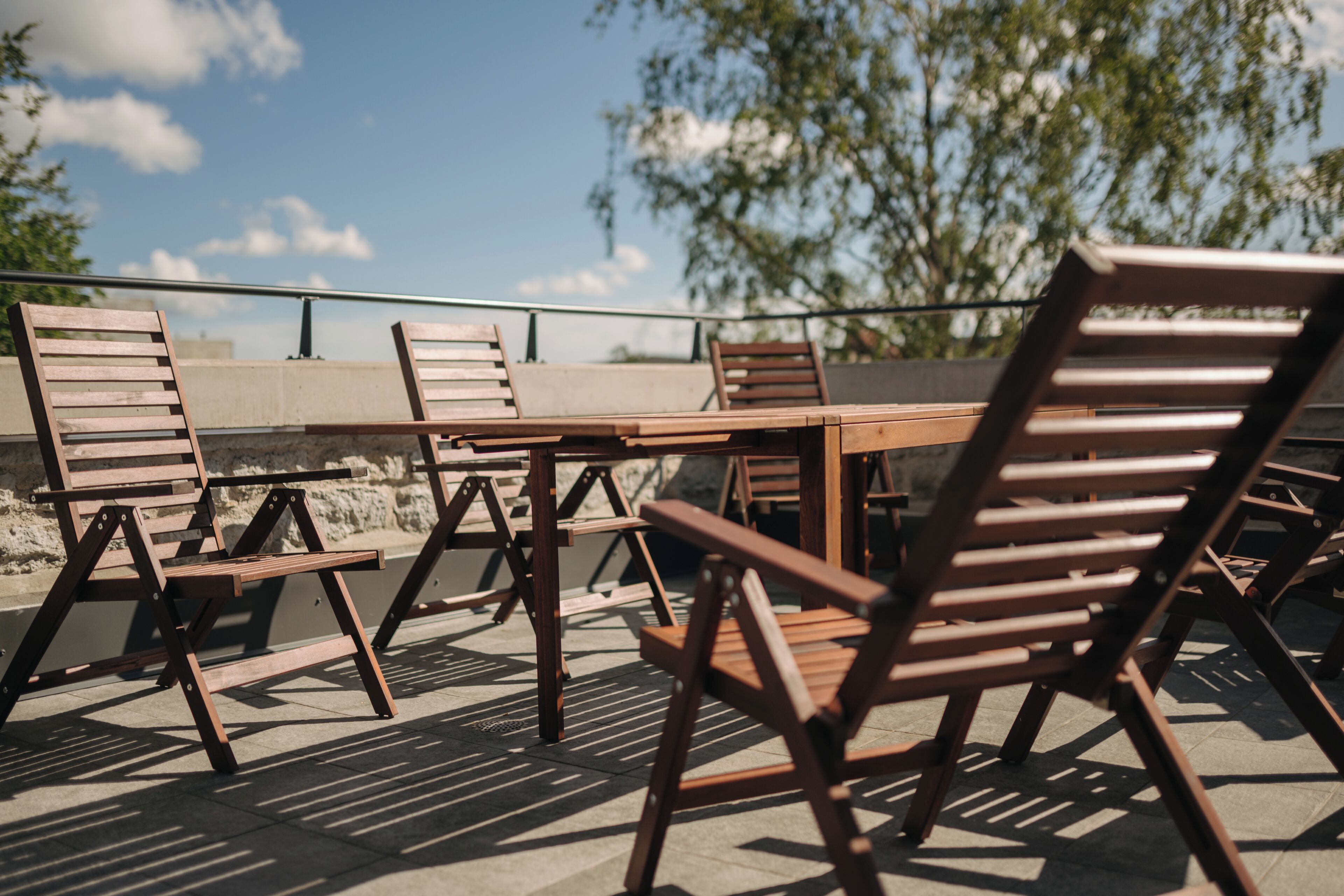 A terrace with wooden furniture and a view of trees.