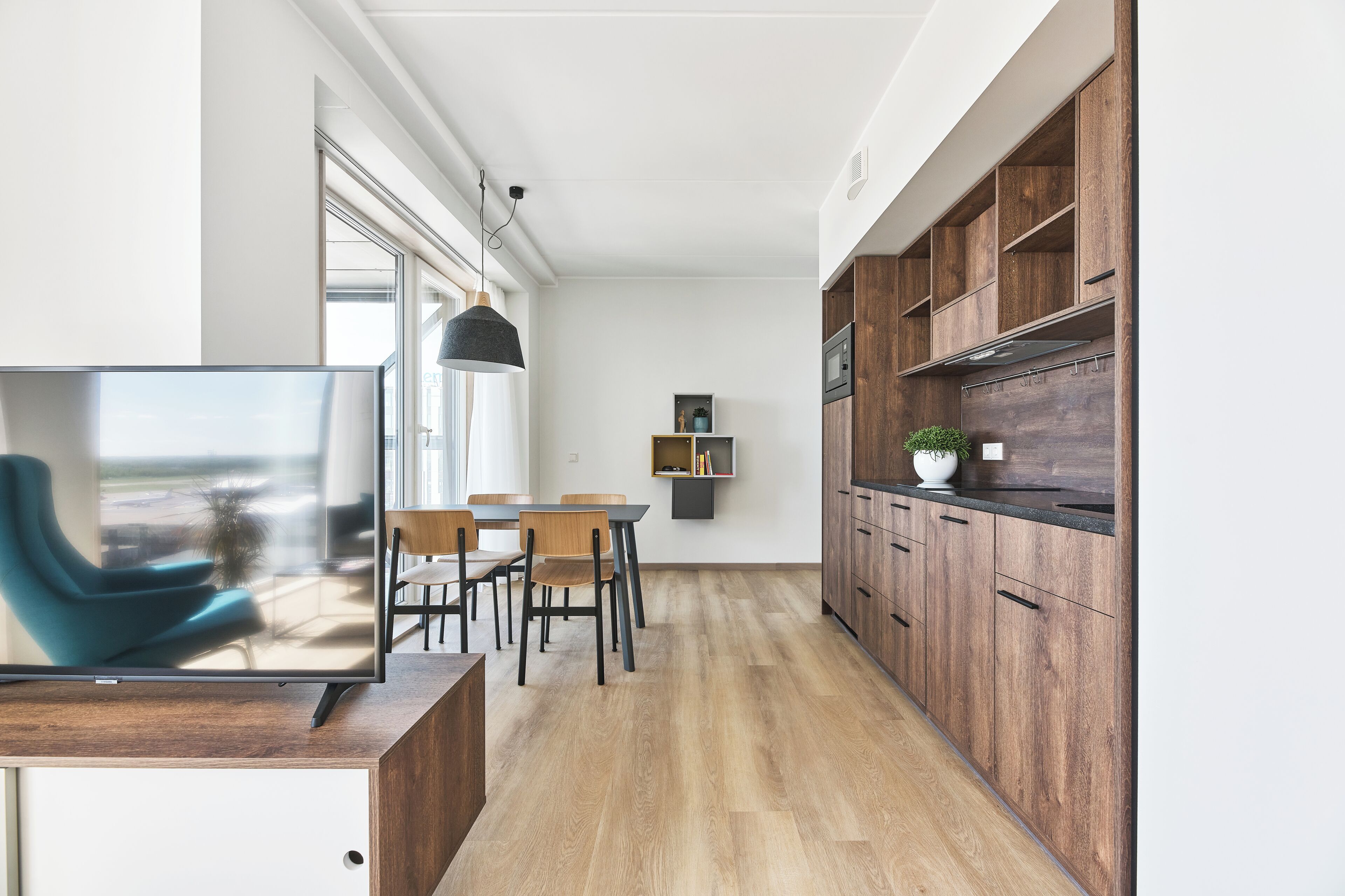 Eine moderne Küche mit Holdekor, Backofen und einer Essecke inklusive Fernseher und Stühlen.