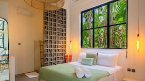 A neatly arranged bedroom with a large window, a bed with white linens, and a wall-mounted shelf. - MariNara Lofts (Canggu)