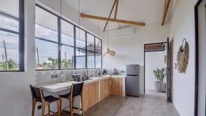 A modern kitchen with large windows, wooden cabinets, and a built-in refrigerator. - MariNara Lofts (Canggu)