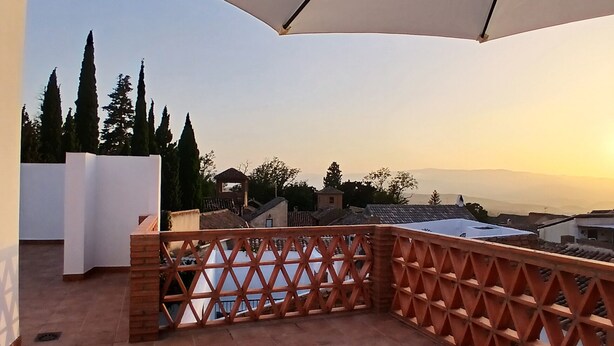 Una terrazza con vista sulla città, una recinzione in legno a graticcio e due poltrone da relax.