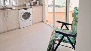 Una cucina compatta con lavatrice, forno a microonde e un'area pranzo con una sedia.