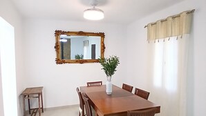 Una sala da pranzo con un tavolo e sedie in legno, un tavolino, uno specchio e una pianta in vaso.