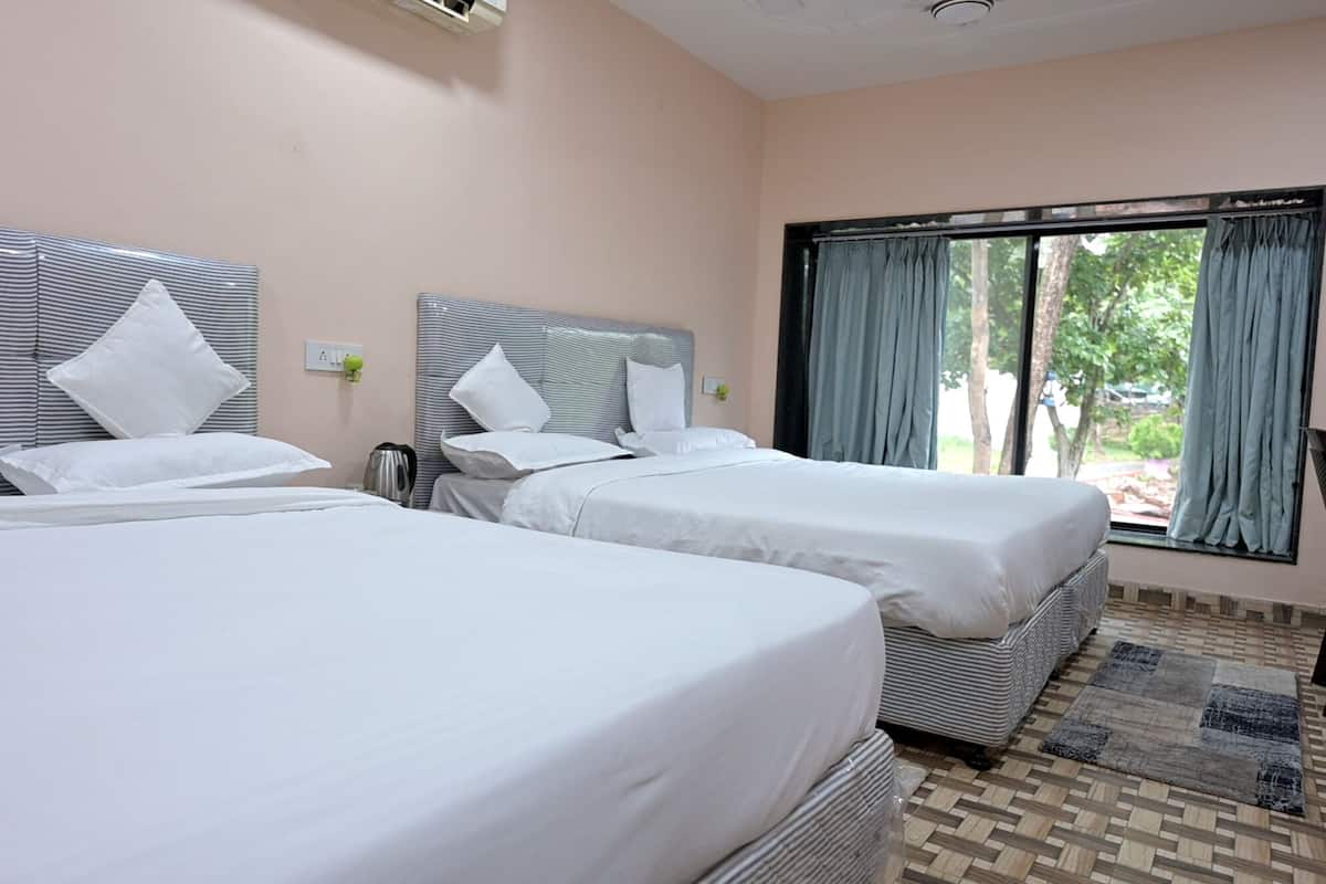 Een hotelkamer met twee eenpersoonsbedden, een raam met gordijnen, een tafeltje en een stoel.