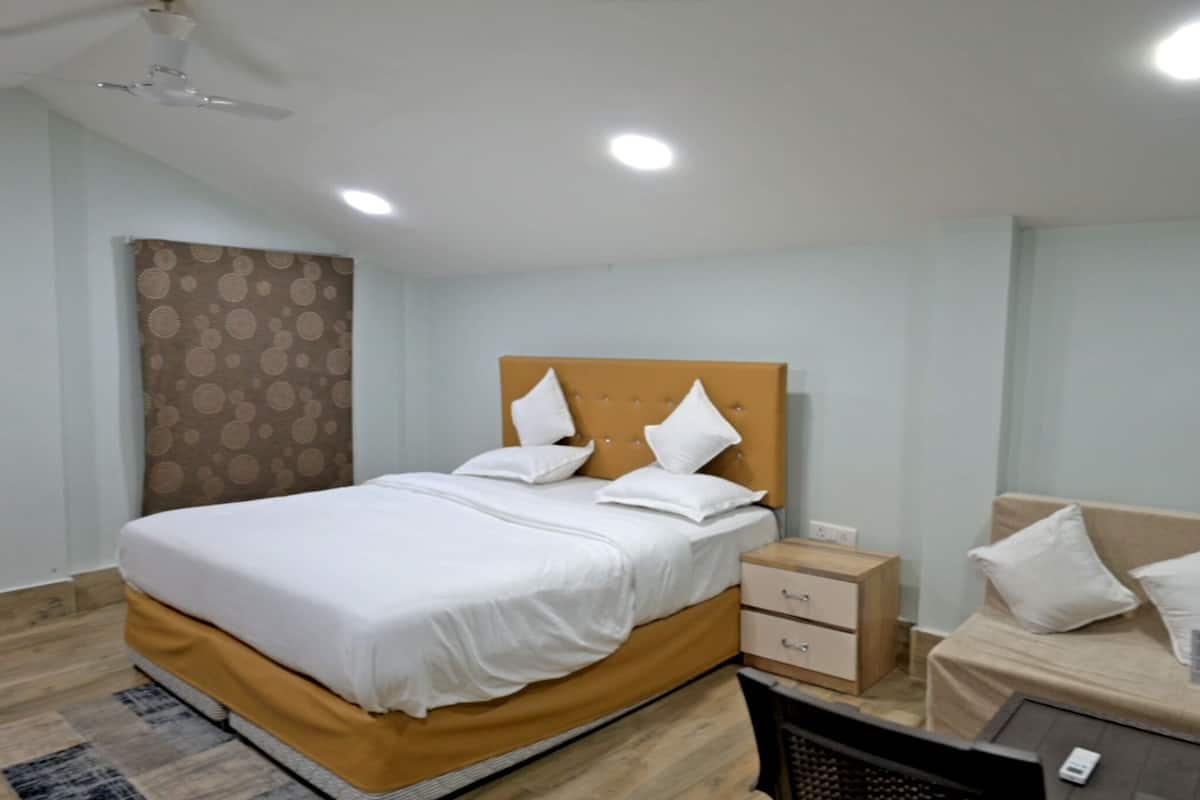 Een hotelkamer met een bed, nachtkastje en een sofa.