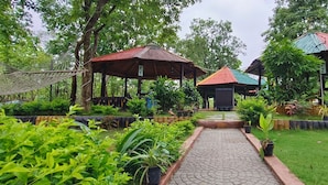 A garden with a paved walkway, several gazebos, and lush greenery. - Resort Nature Camp - Jatmai (Chhura)