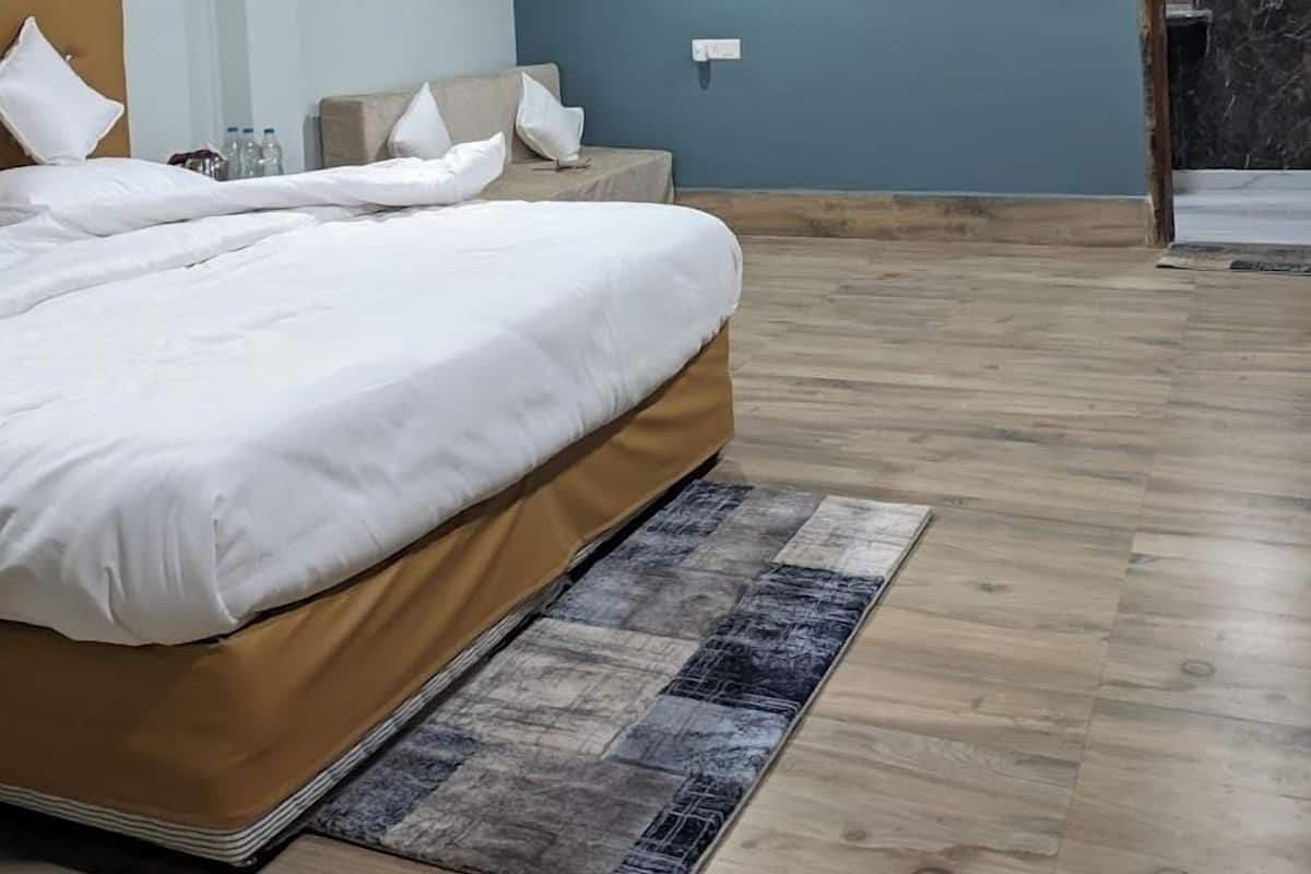 Een slaapkamer met een bed, een plafondventilator, een airconditioning en een houten vloer.