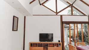 A room with a TV on a wooden cabinet, white walls, and a wooden ceiling structure. - Ningaloo Villa (Gili Trawangan)
