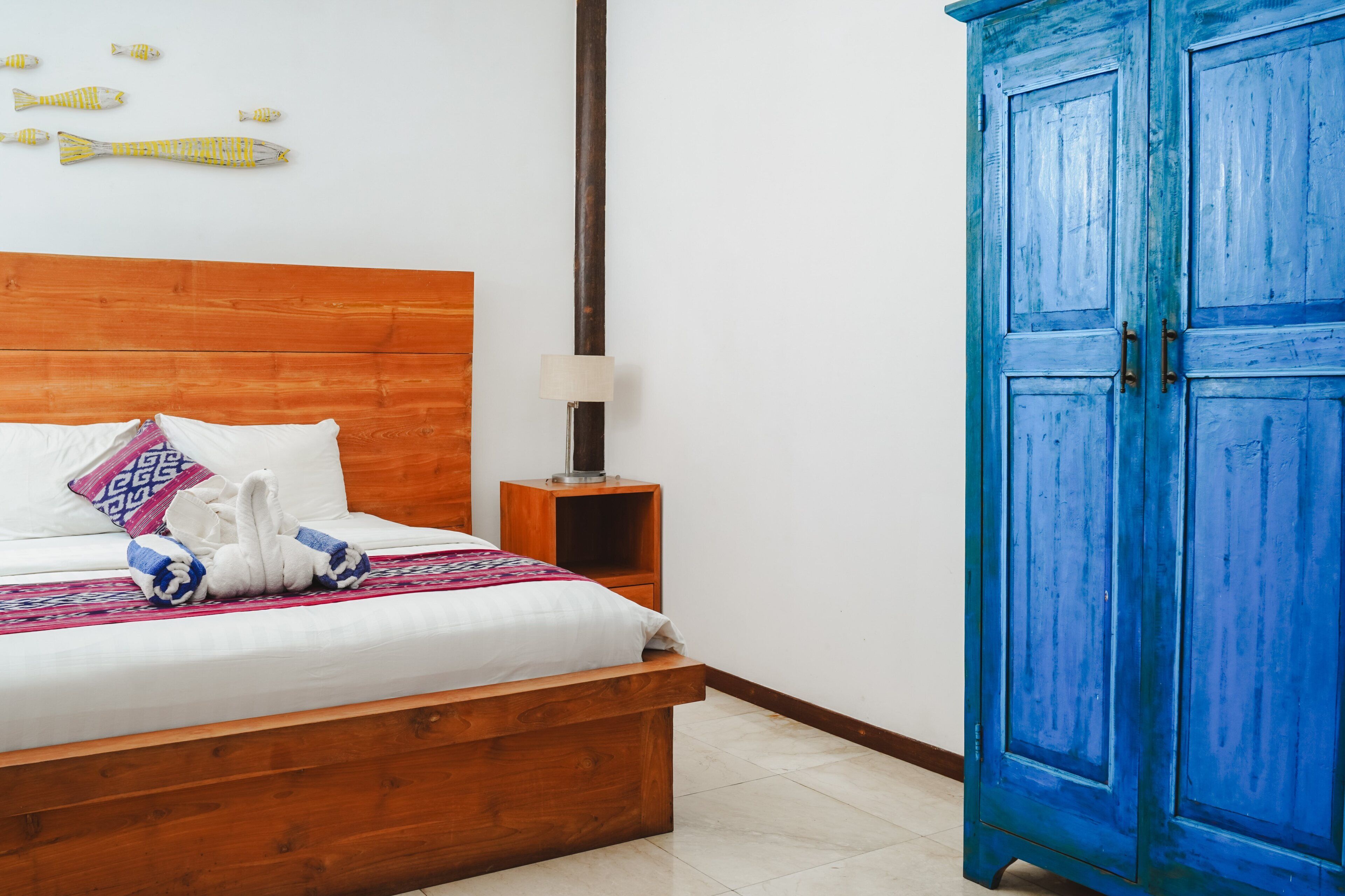 Une chambre à coucher avec un lit en bois, une table de chevet, une lampe et une armoire bleue.