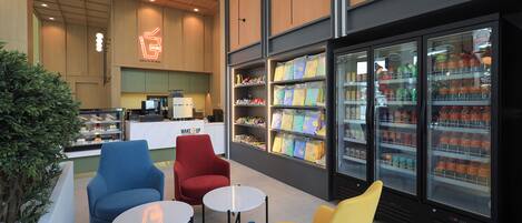A modern cafe with seating, a counter, and a refrigerated beverage display.