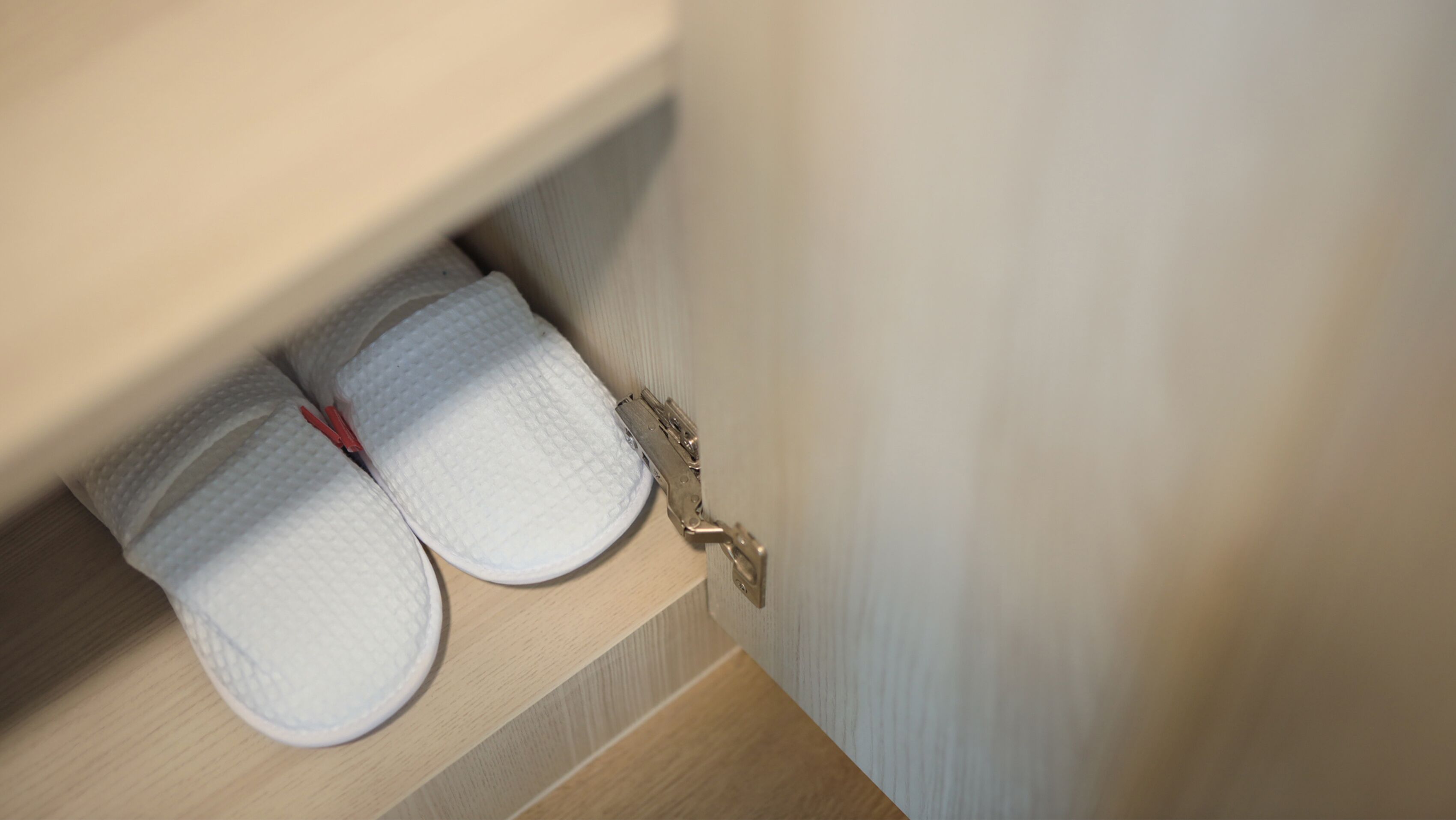 Un coin de pièce avec une étagère en bois sur laquelle sont posés deux serviettes blanches et un crochet en métal.