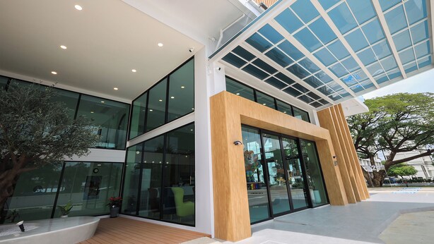 A modern building with large glass windows, a wooden facade, and a covered entrance. - B2 Ubon Airport Premier Hotel (Ubon Ratchathani)