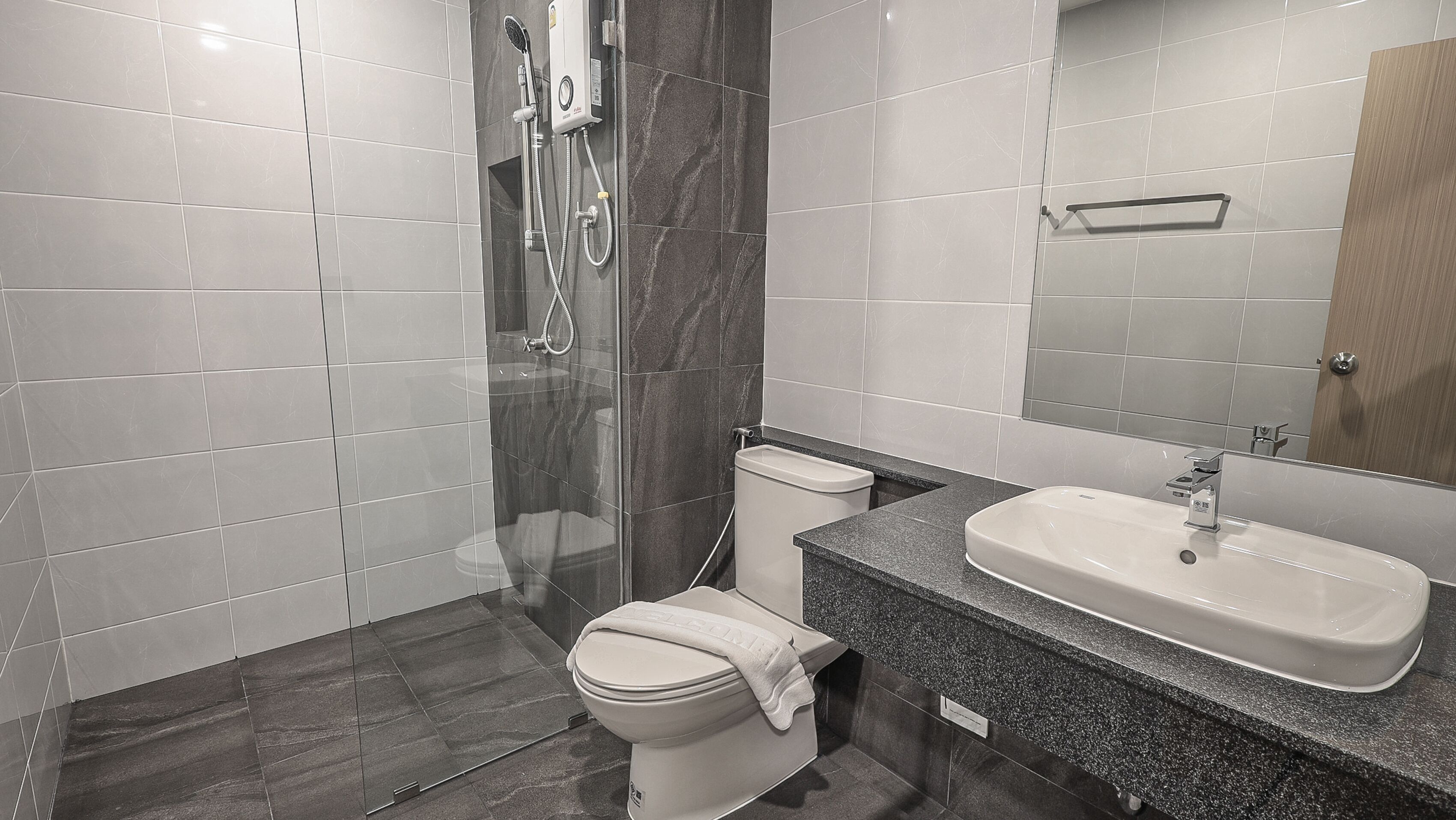 Un baño moderno con ducha de vidrio, inodoro y lavamanos con espejo.
