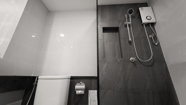 A modern bathroom with a shower, toilet, and a towel dispenser.