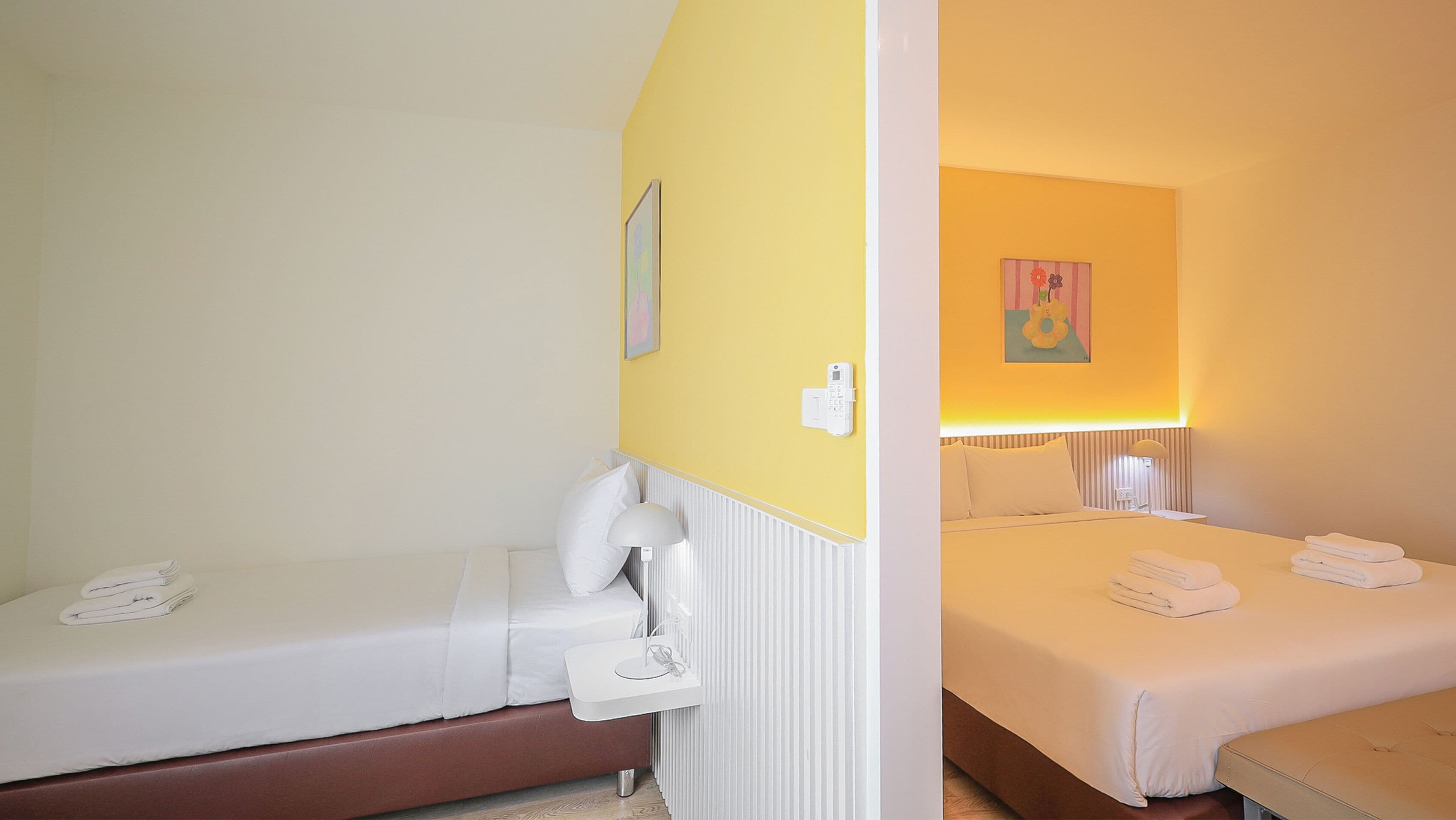 Habitación de hotel con dos camas, una mesita de noche con lámpara y un teléfono en la pared.