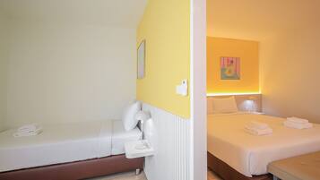 Habitación de hotel con dos camas, una mesita de noche con lámpara y un teléfono en la pared.