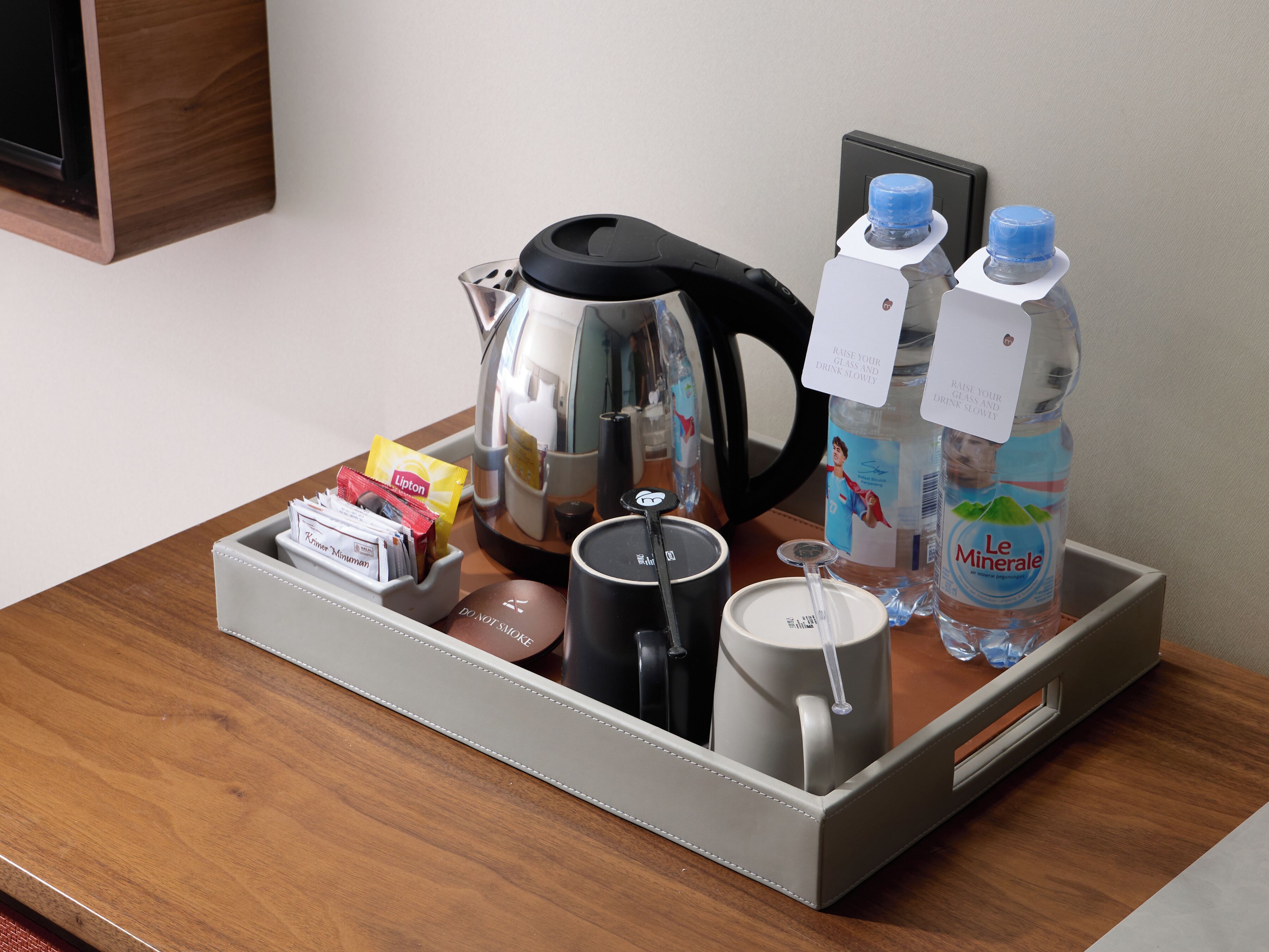 Een dienblad met een koffiezetapparaat, een mok, Lipton theezakjes, een klein doosje en twee waterflessen.