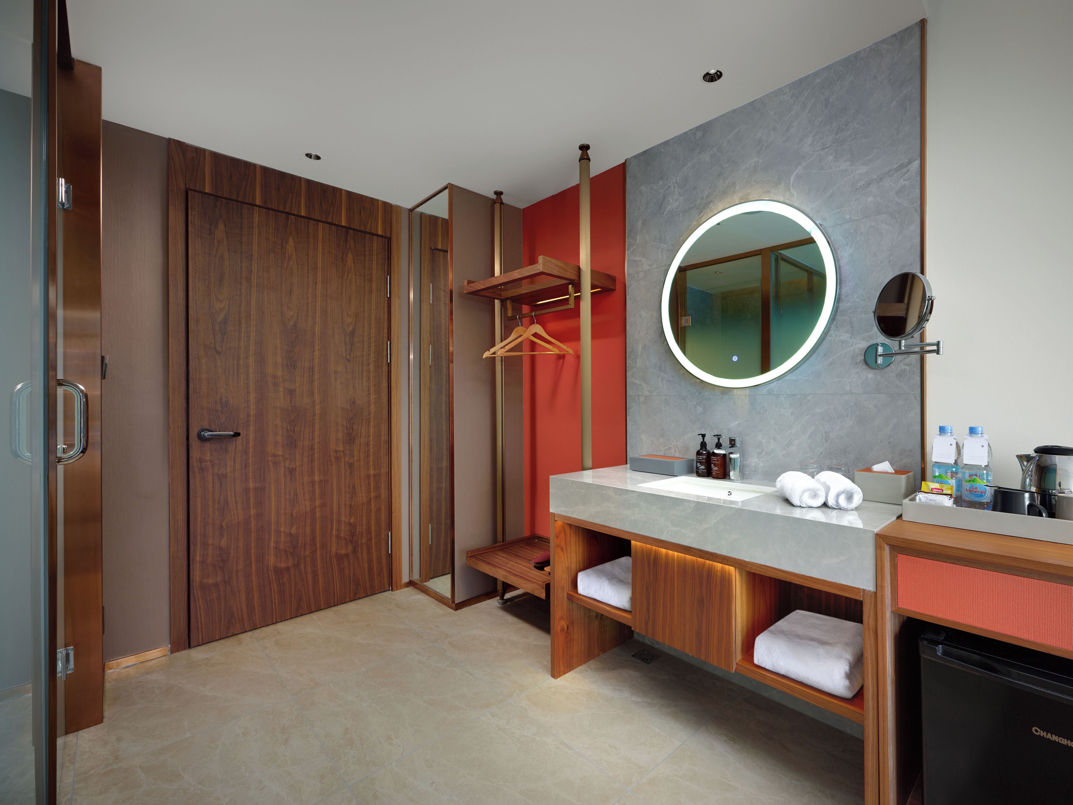 Un baño moderno con tocador de madera, un espejo redondo y un calentador empotrado.