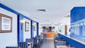 A restaurant with blue and white decor, featuring a bar area and seating along the walls.