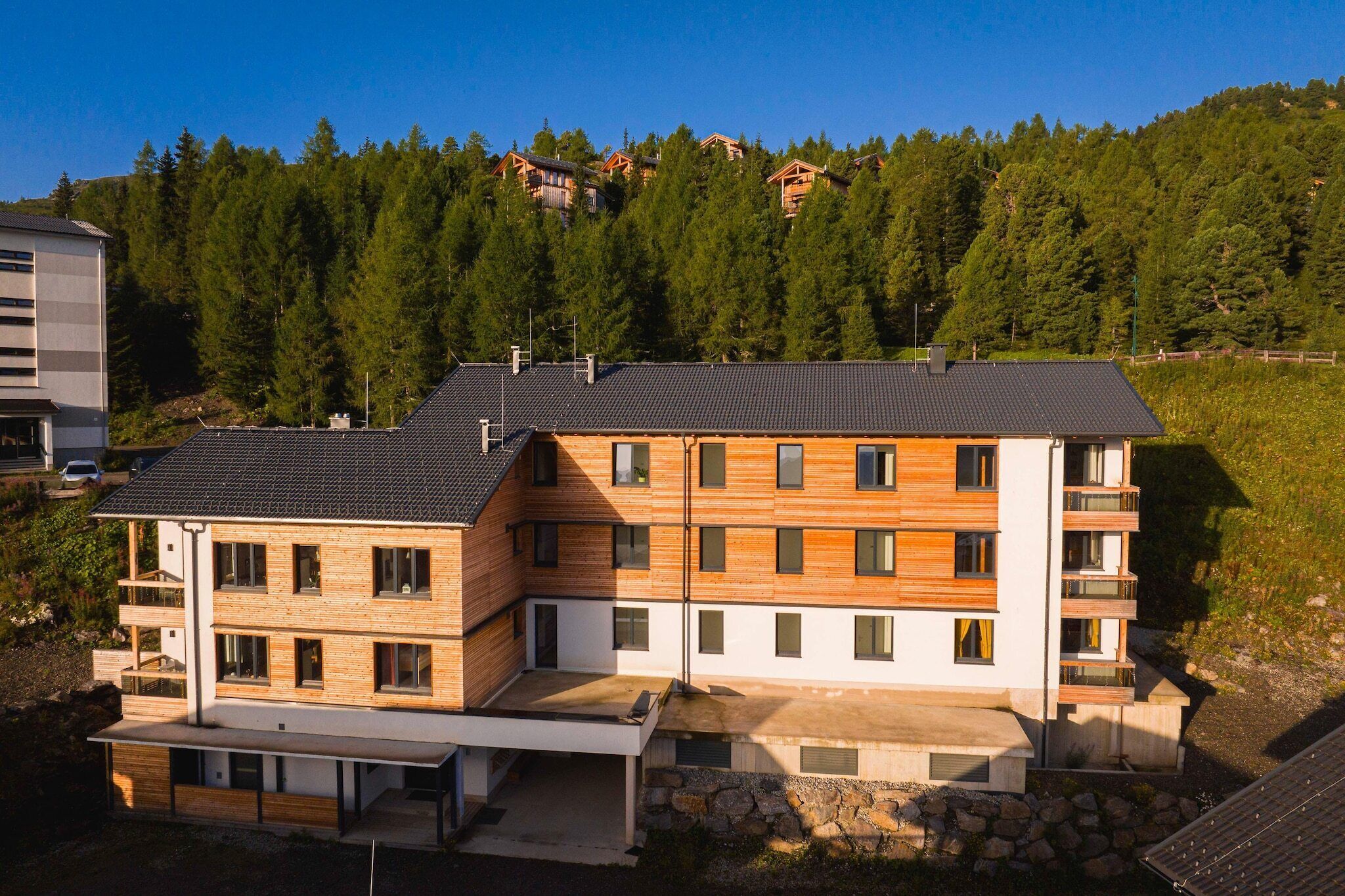 Ein mehrstöckiges Gebäude mit Flachdach, Holzfassade und Balkonen.