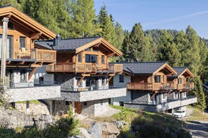 A multi-story chalet with wooden balconies and stone foundations, set in a forested area. - Attractive chalet on the ski-slopes (Turracher Höhe)