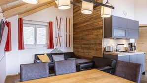 A modern interior with a wooden ceiling, a dining area with a wooden table, a kitchen with grey cabinets, and a ski-themed wall decoration. - Inviting chalet on the ski-slope (Turracher Höhe)