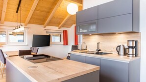 A modern kitchen with wooden beams, grey cabinets, a wooden island, and a flat-screen TV. - Inviting chalet on the ski-slope (Turracher Höhe)