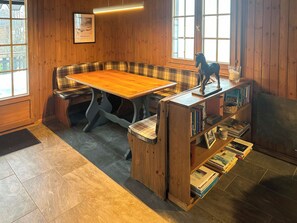 Una stanza accogliente con un tavolo e una panca in legno, una libreria e una finestra con vista.
