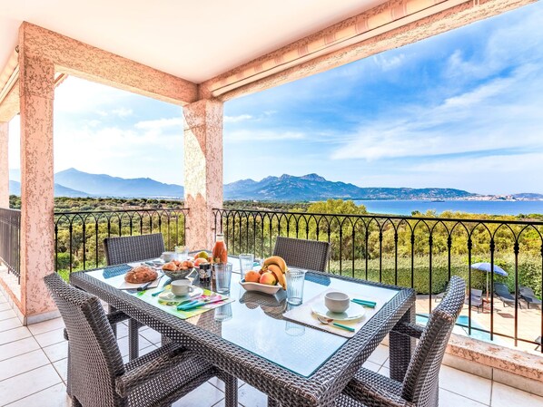 A balcony with a table set for breakfast, overlooking a scenic view of mountains and the sea. - Giulia II by Interhome (Lumio)
