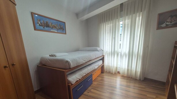 A bedroom with a bed, a wardrobe, and a window with curtains. - 25A06 Centrico Playa 4 dormitorios Luanco (Luanco)