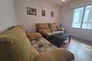 Una sala de estar con un sofá, una mesita de centro y una ventana con cortinas.