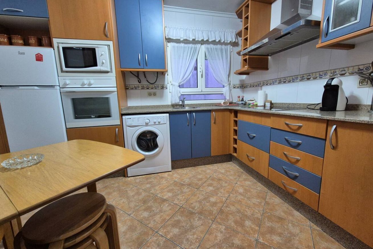 Uma cozinha compacta com máquina de lavar, micro-ondas e cafeteira.