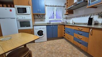 Uma cozinha compacta com máquina de lavar, micro-ondas e cafeteira.