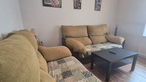 A living room with a sofa, a coffee table, and a lamp. - 25A06 Centrico Playa 4 dormitorios Luanco (Luanco)