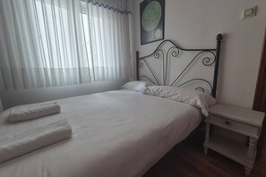 A bedroom with a bed, white linens, a nightstand, and a wall-mounted globe.
