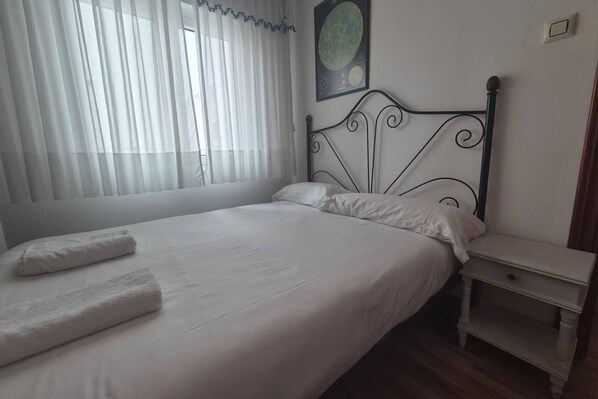A bedroom with a bed, white linens, a nightstand, and a wall-mounted globe.