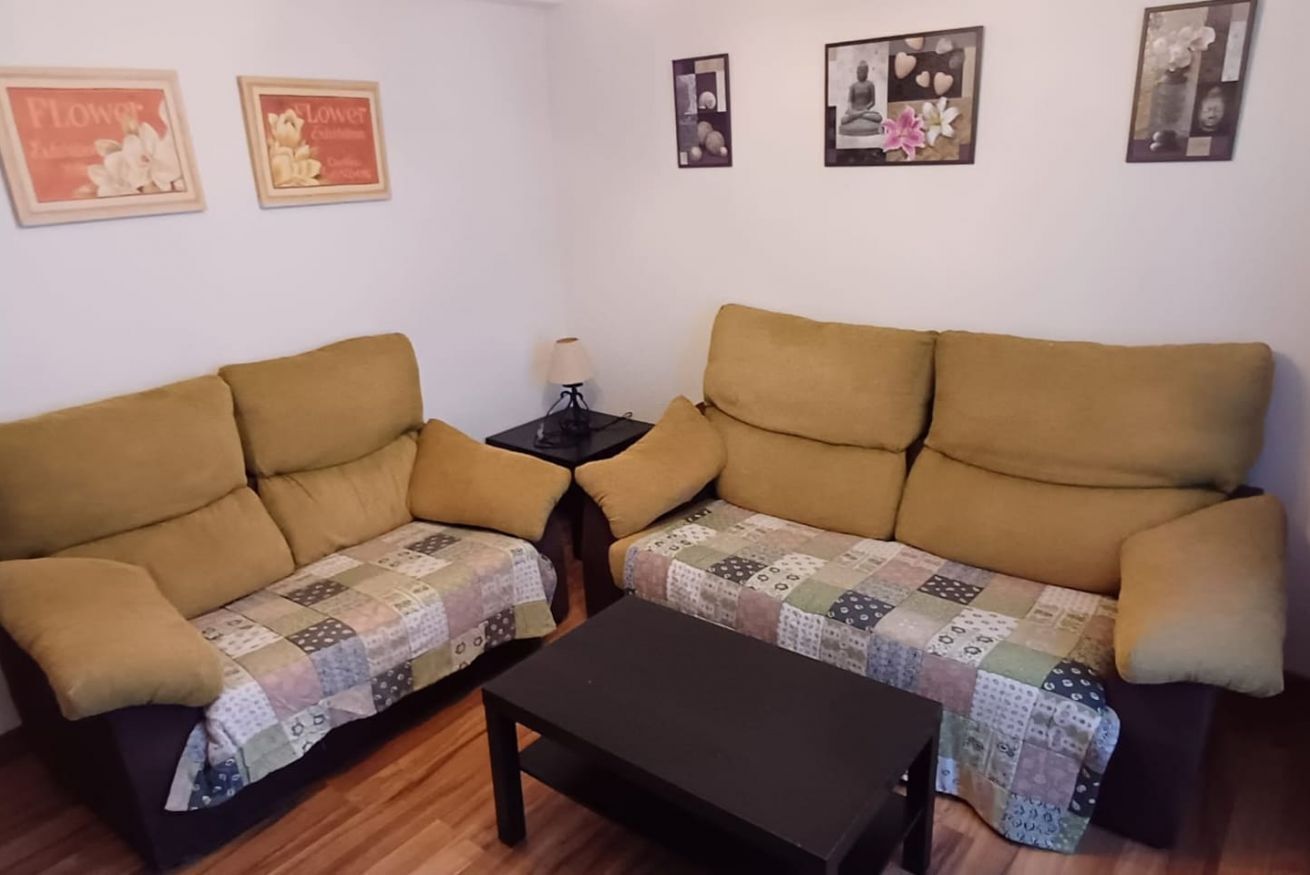Uma sala de estar com dois sofás, uma mesa de centro e quadros nas paredes.