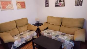 Uma sala de estar com dois sofás, uma mesa de centro e quadros nas paredes.