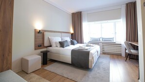 A modern bedroom with a bed, bedside table, and a window with curtains. - Simma Luxury Apartments & Rooms (Belgrade)