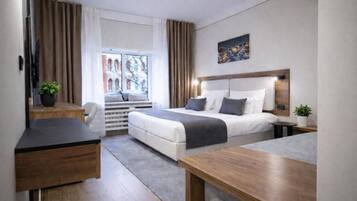 Una habitación de hotel moderna con cama, mesita de noche, escritorio y ventana con cortinas.