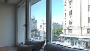 A room with a large window, a sofa, and a view of a cityscape. - Simma Luxury Apartments & Rooms (Belgrade)