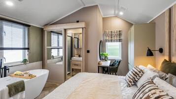 Une chambre avec un grand lit, une baignoire, un bureau et une fenêtre avec des stores.