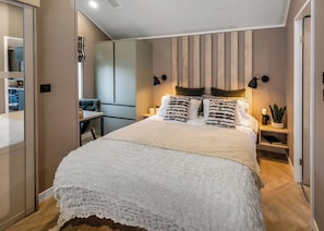 Une chambre moderne avec un grand lit, des lampes de chevet, une table de chevet et un miroir.