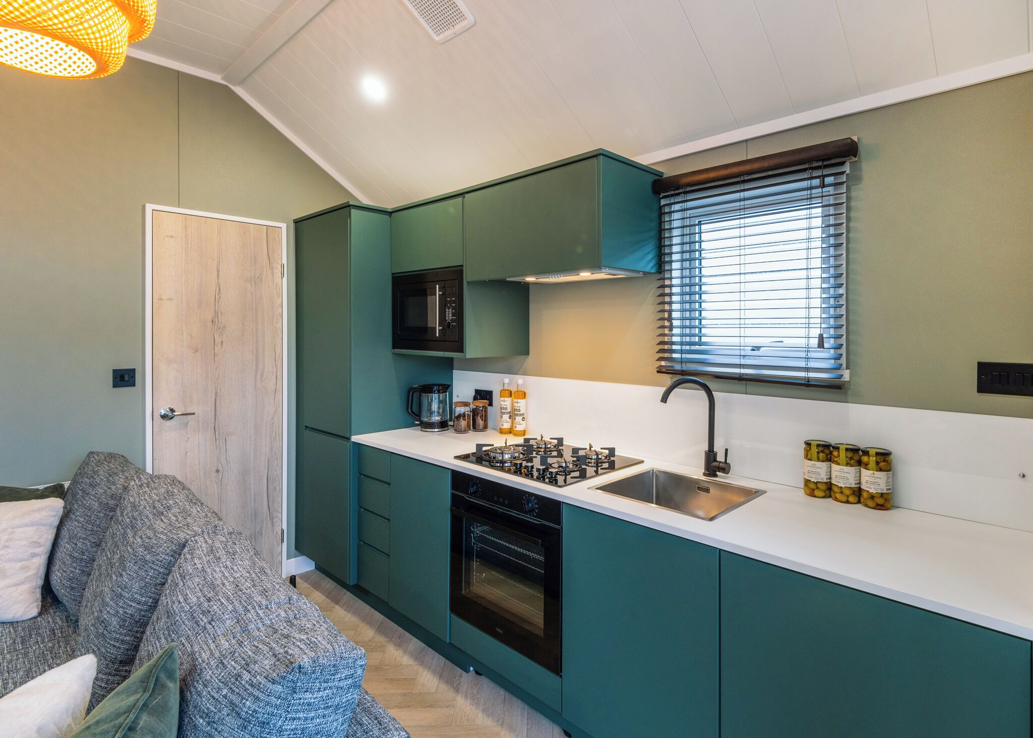 Une cuisine de taille réduite avec des meubles de couleur turquoise, un four à micro-ondes, une cuisinière et un évier.